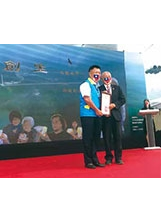 李副主委（左）在「創生｜心在太平」微電影首映會上，向嚴村長（右）致敬，感謝他創造了太平村的奇蹟。之照片