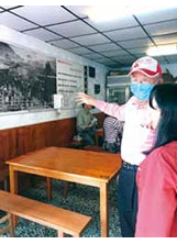嚴村長化身導遊，在太平老街一間老鋪裡，向遊客詳細解說老照片中的老故事。之照片