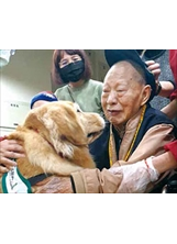 彰化榮家失明的的劉伯伯，擁抱輔療犬貝貝，洋溢著愉快的心情。（圖／彰化榮家，攝於戴口罩規定加嚴前）之照片
