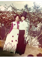 當年畢業晚會上的一對搭檔，作者陳秀竹（左）身穿白色長裙，同學朱明珍（右）頭戴黑色高帽扮紳士。（圖／陳秀竹）之照片