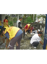 南投縣榮服處榮欣志工與學生志工，為單身獨居榮民李家清住家庭院鋪設水泥。（宋懷錦攝）之照片