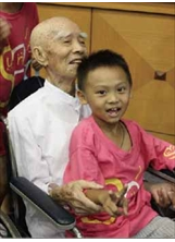 九十七歲的鄧榮華老先生（左）抱著可愛的孩童，笑得合不攏嘴。（蔡淑玲攝）之照片