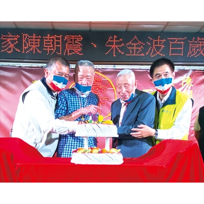 吳副主委（左一）和板橋榮家家主任張長林（右一）陪同百歲壽星朱金波（左二）、陳朝震（右二）切蛋糕，祝福他們松柏長青。（圖／板橋榮家）